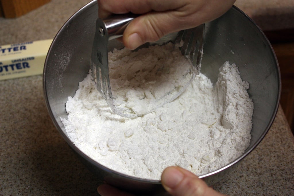 The butter being cut into the flour with a pastry blender.