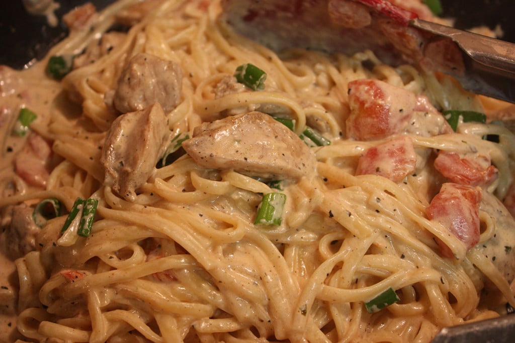 Cajun Chicken Pasta  in a skillet with a wooden spoon.