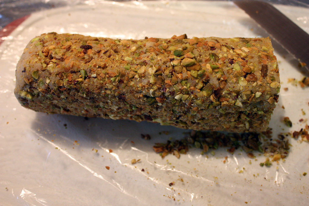 Cardamom Pistachio Cookies dough rolled into a log, covered in pistachio 