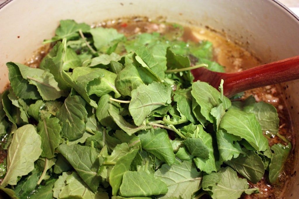 Kale added to the soup pot.