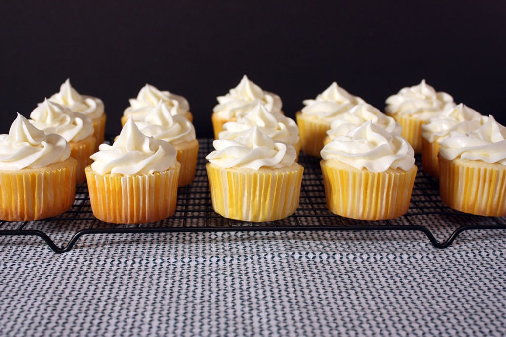 Frosted Lemon Cupcakes lined up on a wire rack.