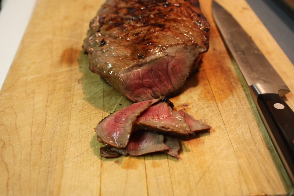 Medium-rare beef on a wooden cutting board.