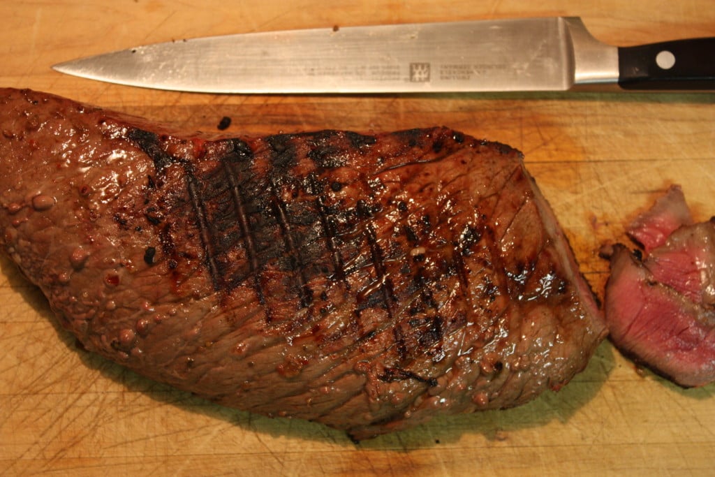 Grilled London Broil on a wooden cutting board.