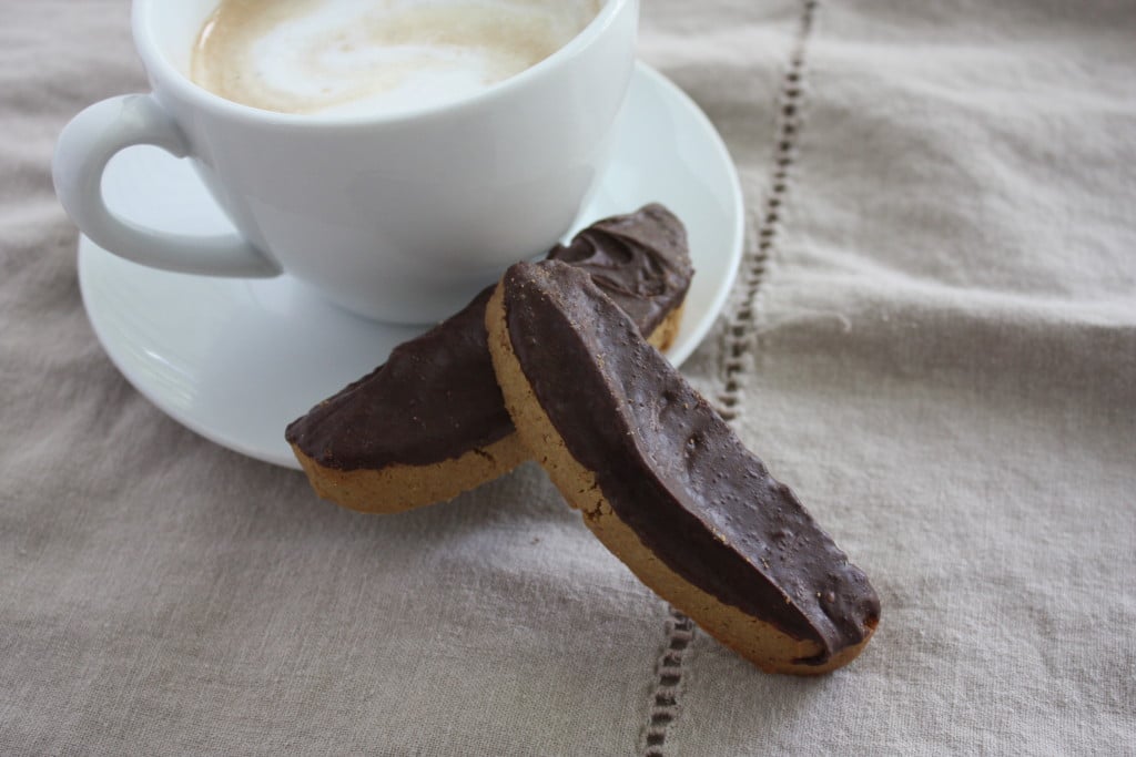 Two Espresso Biscotti leaned against a coffee cup and saucer.