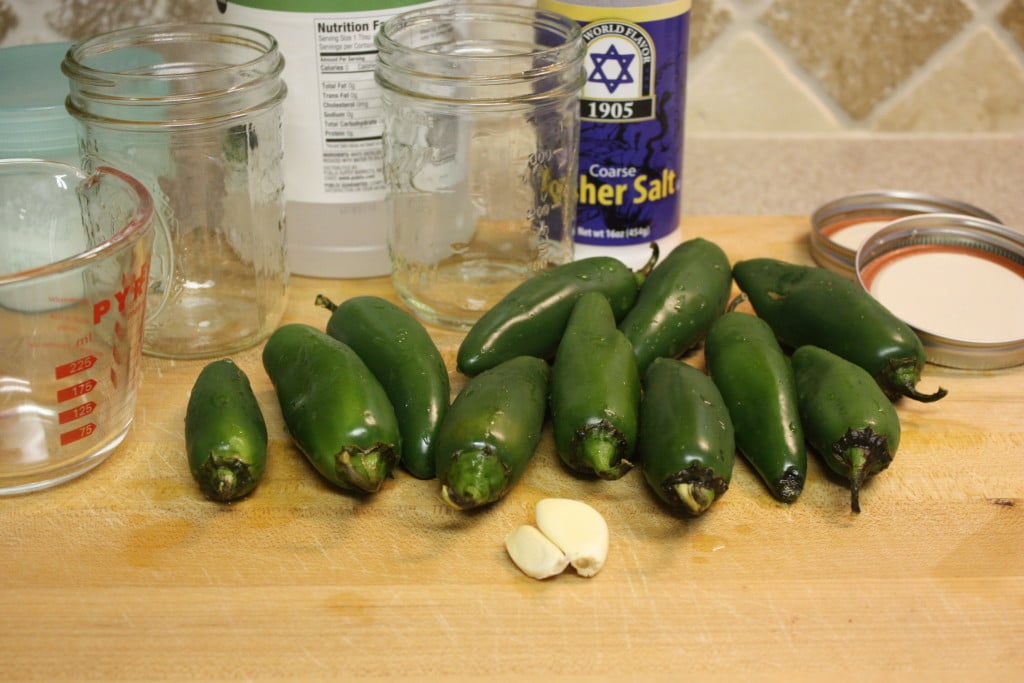 fresh jalapenos and mason jars on a wooden board