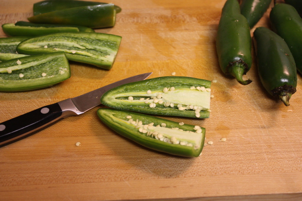 Jalapenos sliced in half on board.