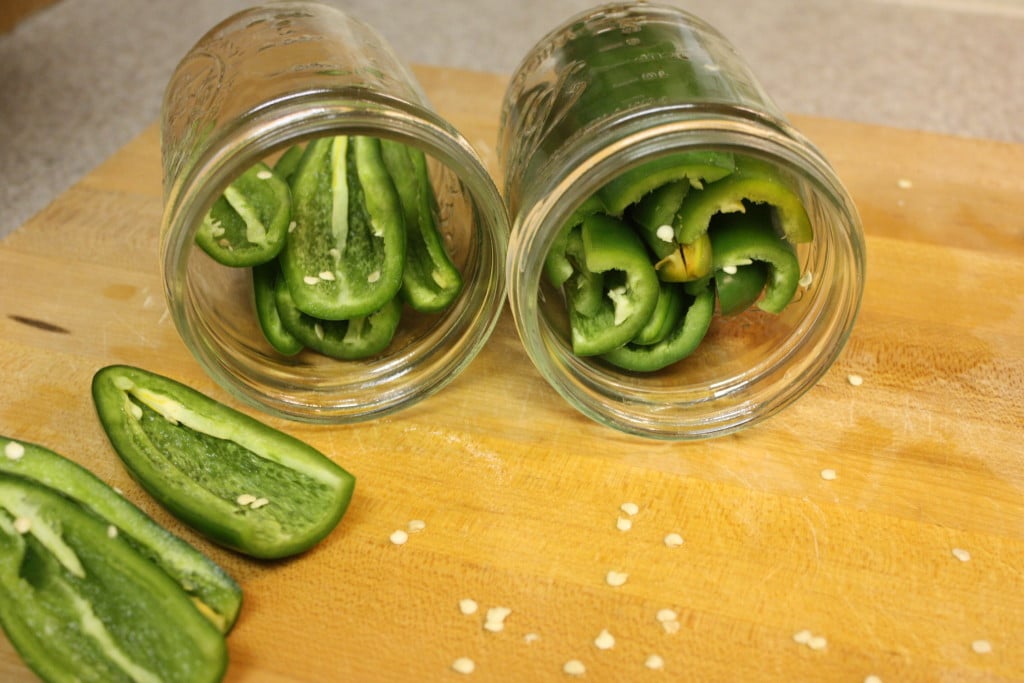 Halved jalapenos stuffed into mason jars.