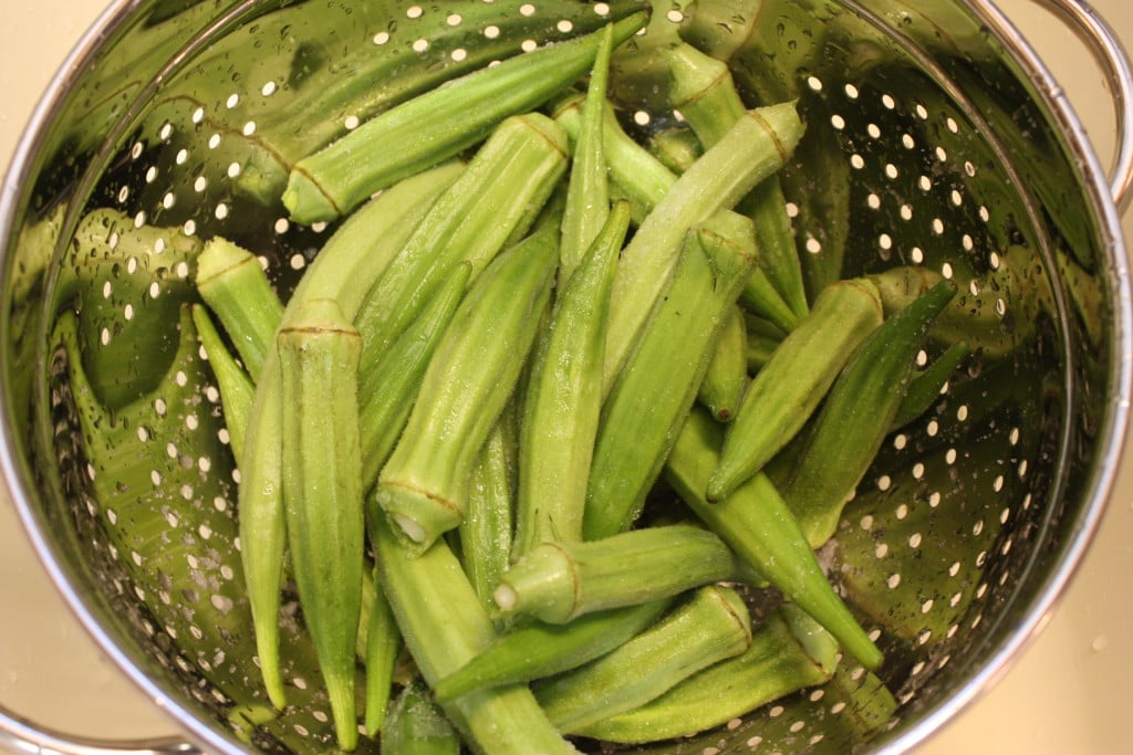 Okra pods in a strainer.