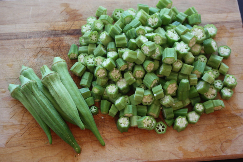 fresh okra pods diced on a wooden cutting board