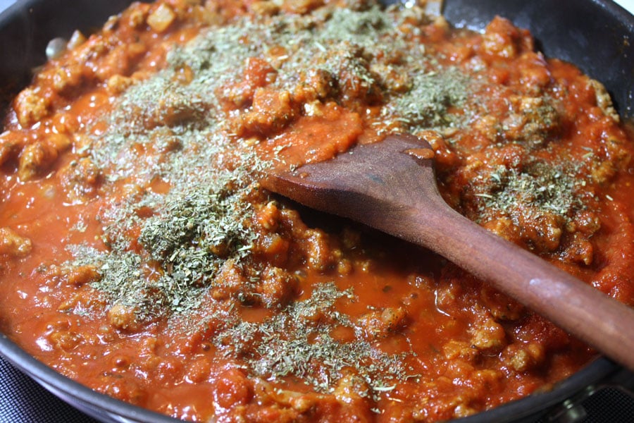 Marinara sauce with seasonings added on top in a skillet.