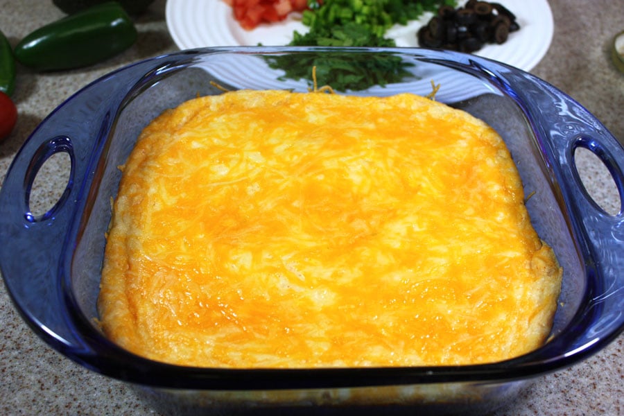 Melted sharp cheddar cheese on top of the other black bean dip ingredient layers.