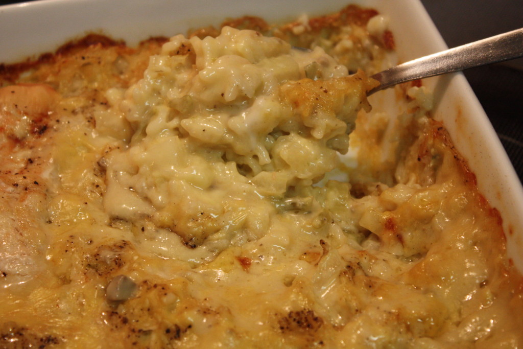 Baked Chicken and Rice being spooned out of the white baking dish.