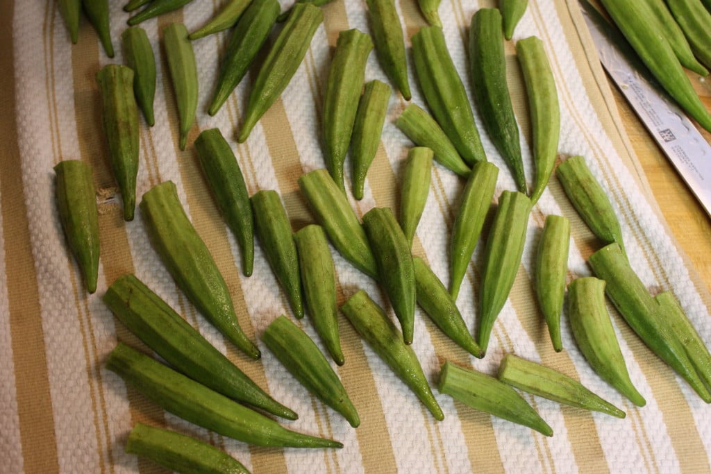 Trimmed fresh okra pods on a kitchen towel.
