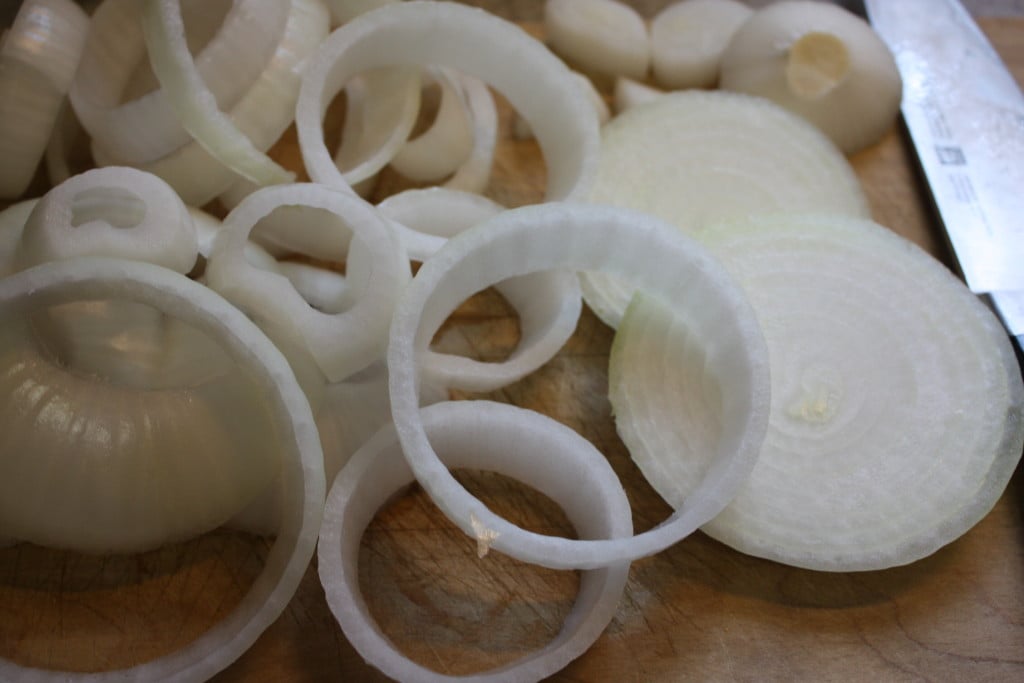 Sliced rings of onion on a wooden board.