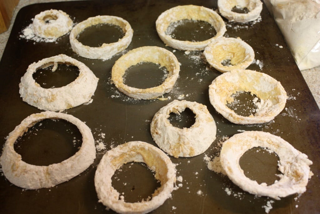 Battered onion rings on a baking sheet.