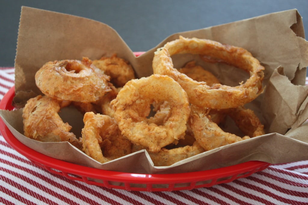 Fried onion rings in a brown paper lined basket.