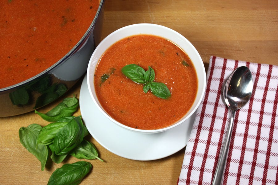 Creamy tomato basil soup in a white bowl garnished with fresh basil.