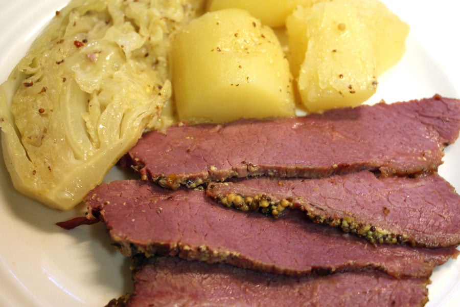 Corned Beef with Mustard Sauce on a white plate with potatoes and cabbage