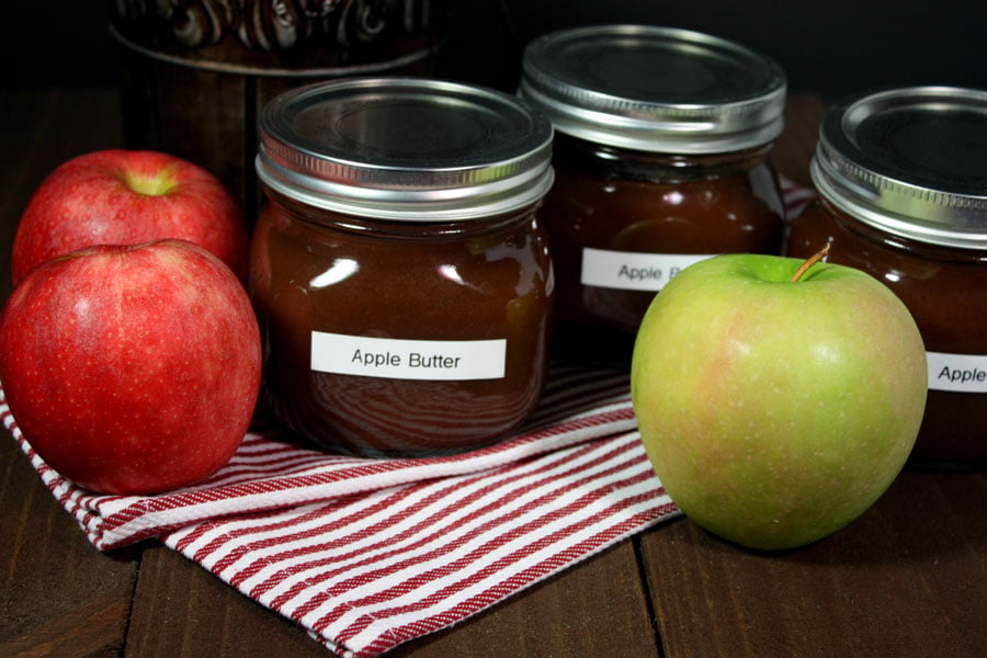 Slow Cooker Apple Butter in mason jars on a red and white striped towel.