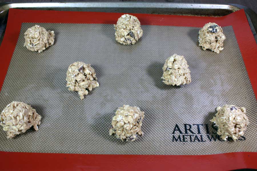 Oatmeal Raisin Cookie dough balls on a silicone baking mat.