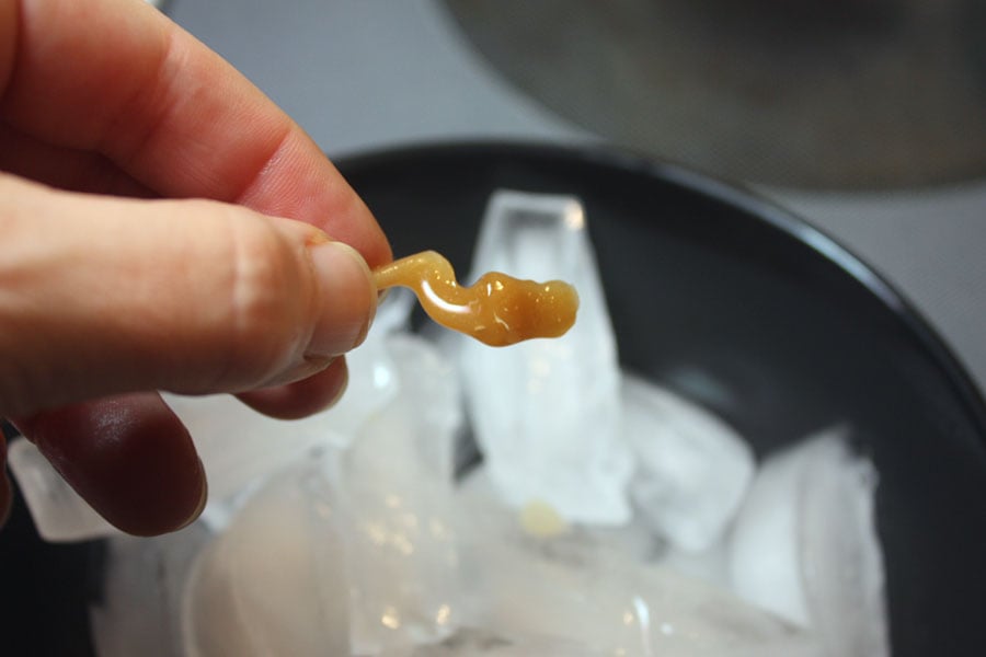 Piece of dripped hard candy being held over the ice.