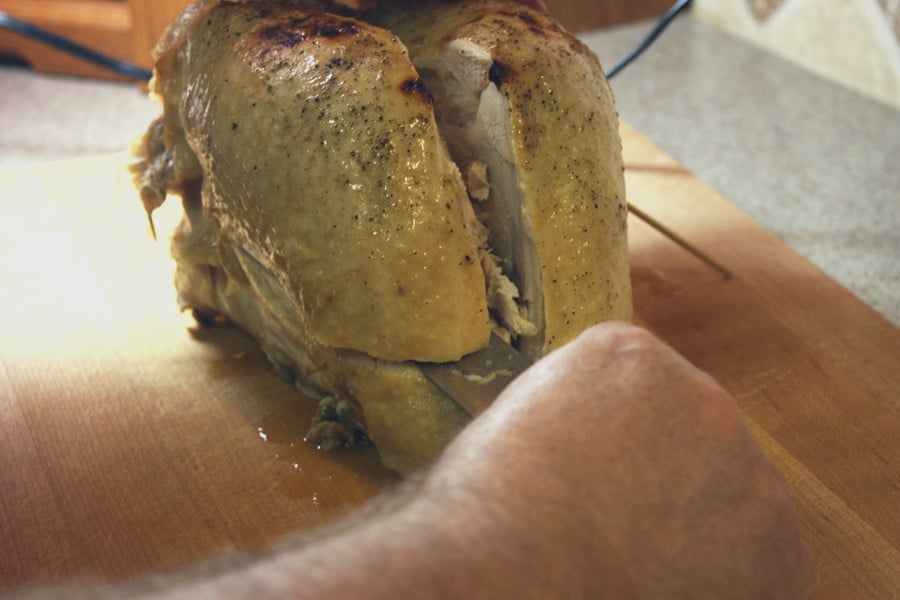 cutting the meat off the turkey breast on a wooden cutting board