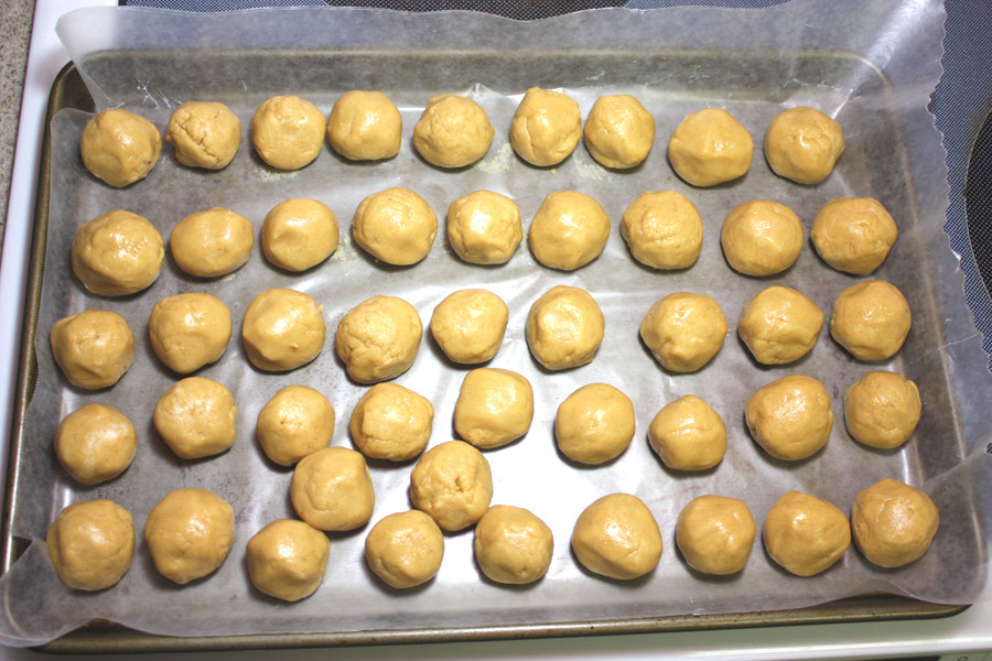 Peanut butter balls formed on a wax paper lined baking sheet.