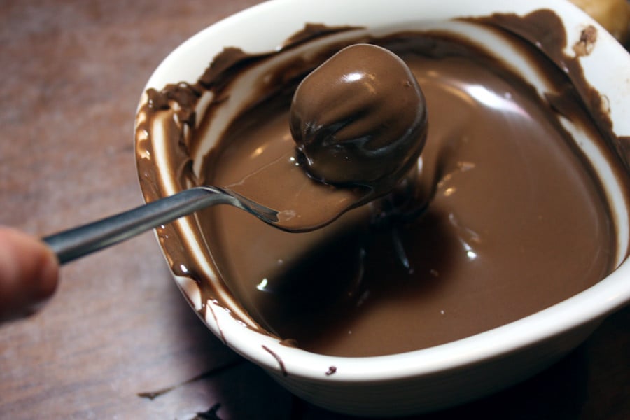 Peanut butter ball being dipped in melted chocolate.