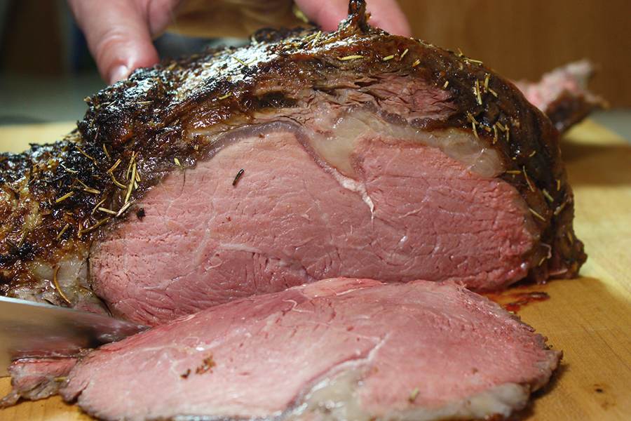 Prime Rib sliced on a wooden cutting board.