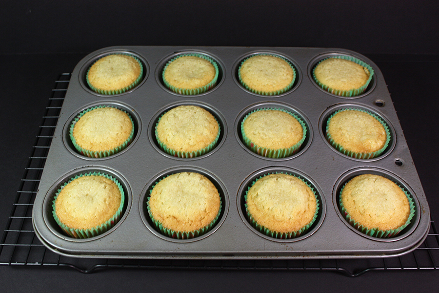 Baked cupcakes in the muffin pan on a wire rack.