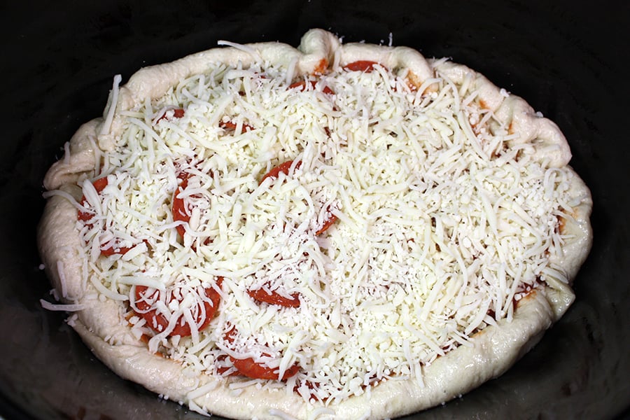 Slow Cooker Pizza dough topped with sauce, pepperoni, and shredded cheese