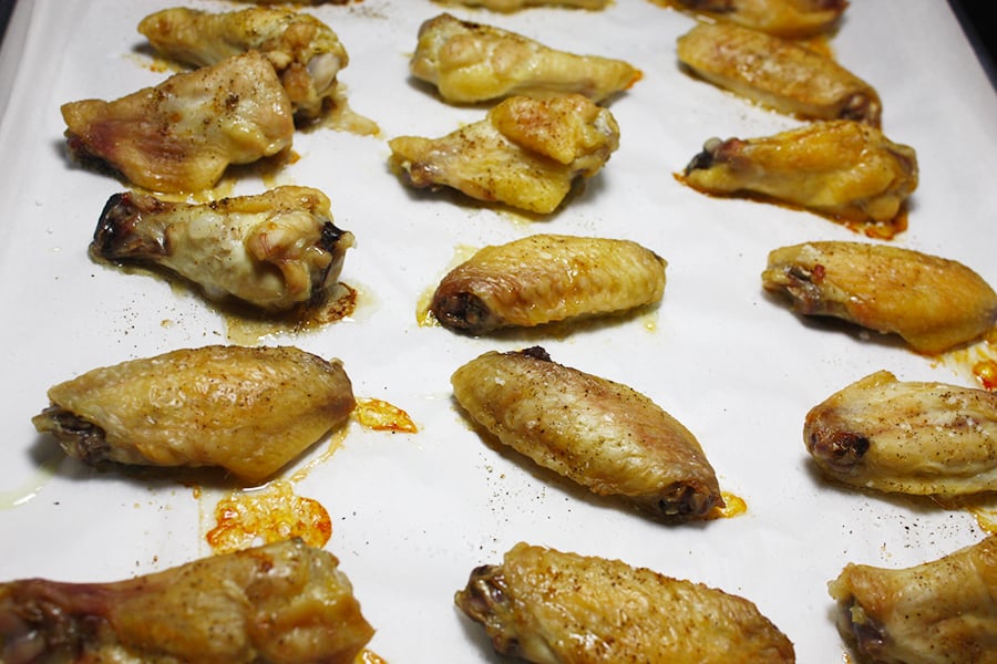 Baked wings on parchment lined baking sheet.