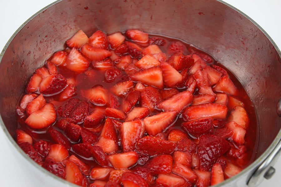 fresh cut strawberries in sautepan with syrup