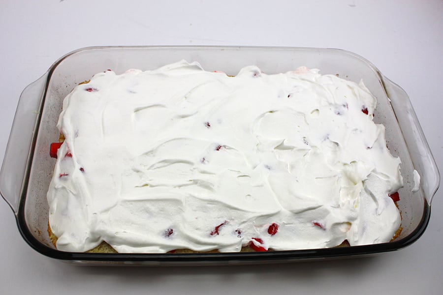 Whipped cream topping spread over the top of the cut strawberries.