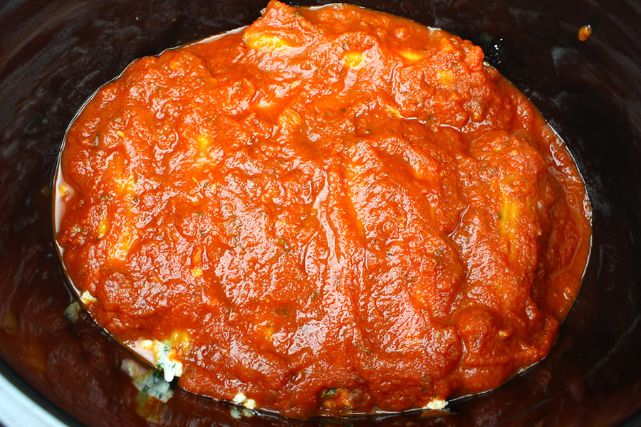 Spinach Ricotta Manicotti top with marinara sauce in the crock of a slow cooker