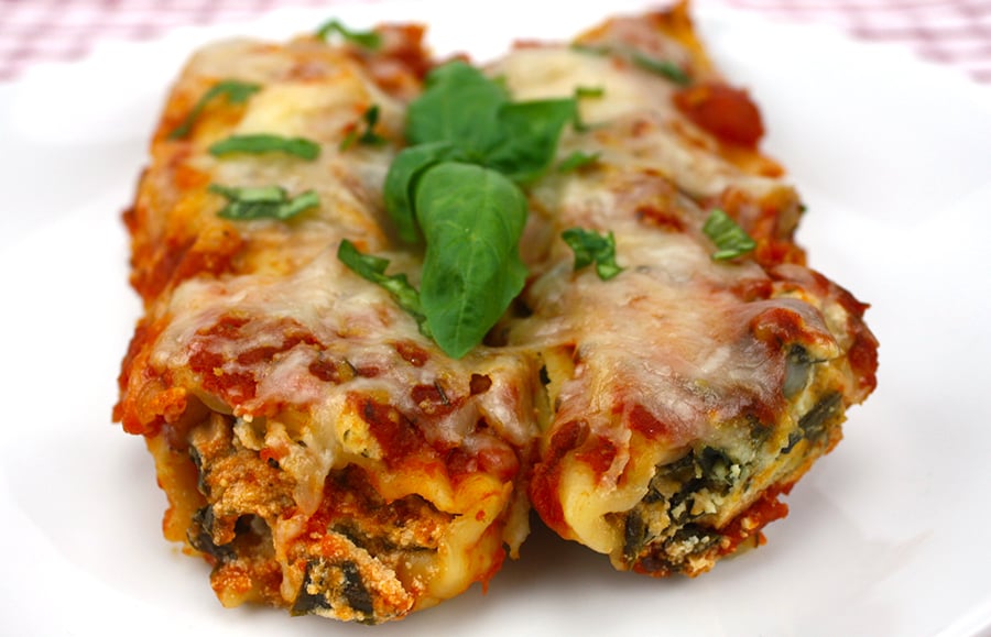 Slow Cooker Spinach Ricotta Manicotti on a white plate garnished with fresh basil leaves