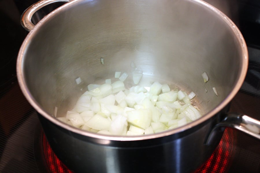 Vegetable Dumpling Soup - onions sautéing in a large metal pot