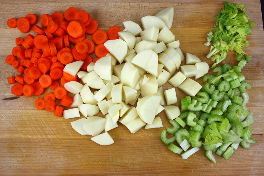 Vegetable Dumpling Soup - diced carrots, potatoes, and celery on a wooden cutting board