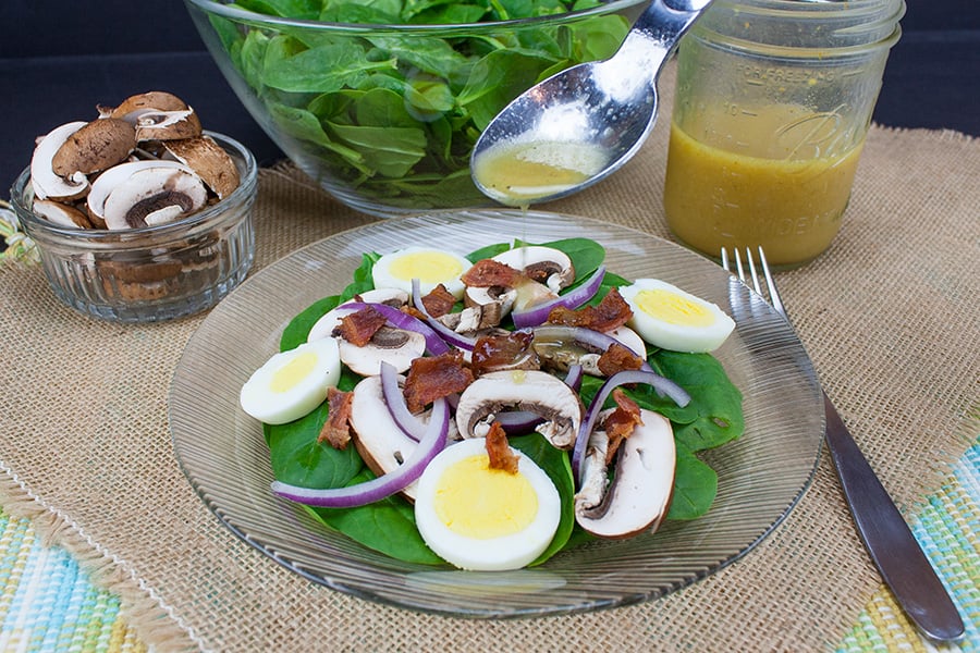 Spinach Salad with Curry Mustard Vinaigrette - vinaigrette being drizzled over the salad
