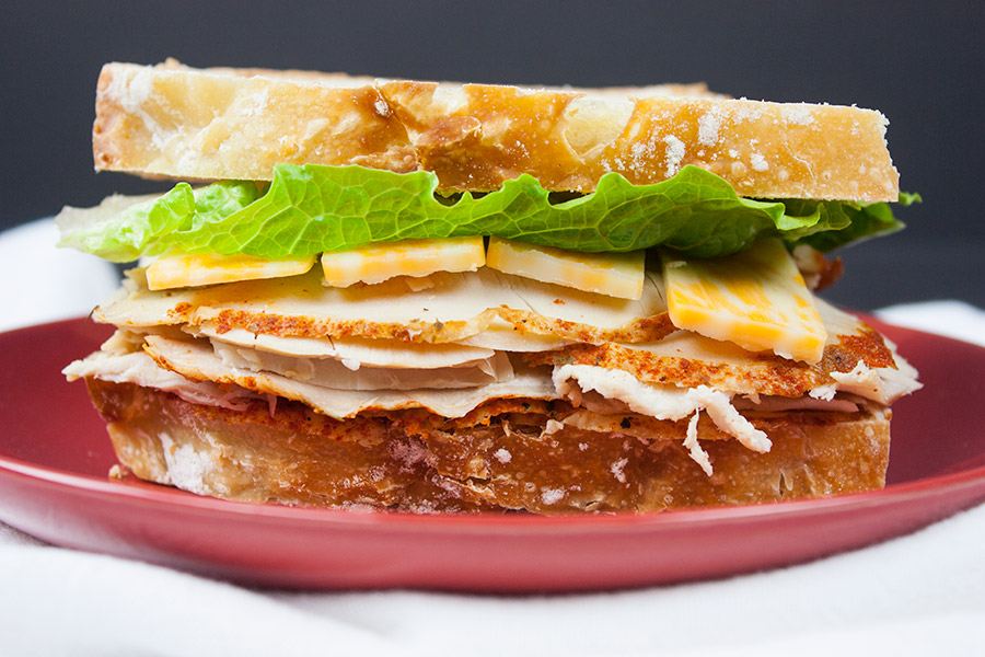 Homemade Cajun Turkey Deli Meat made into a sandwich on a red plate