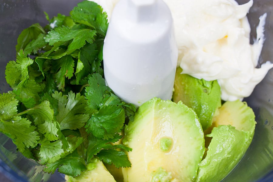 Sour cream, mayonnaise, avocado, cilantro, lime juice, and salt in the bowl of a food processor.