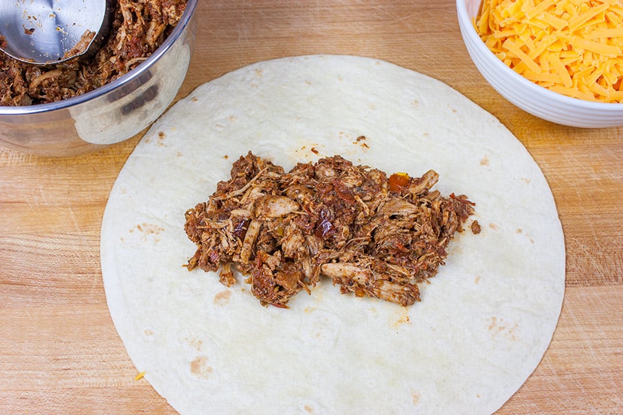 Shredded Mexican chicken in the center of a flour tortilla.