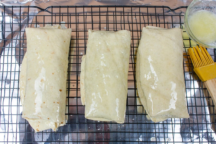 Baked Chicken Chimichangas - unbaked chimichangas on a wire rack brushed with butter