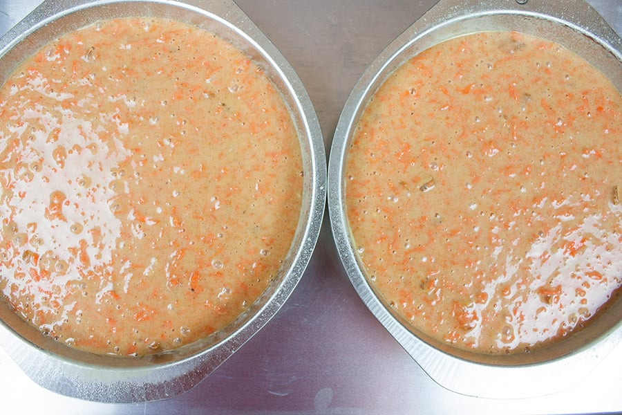 Carrot cake batter divided into metal cake pans.