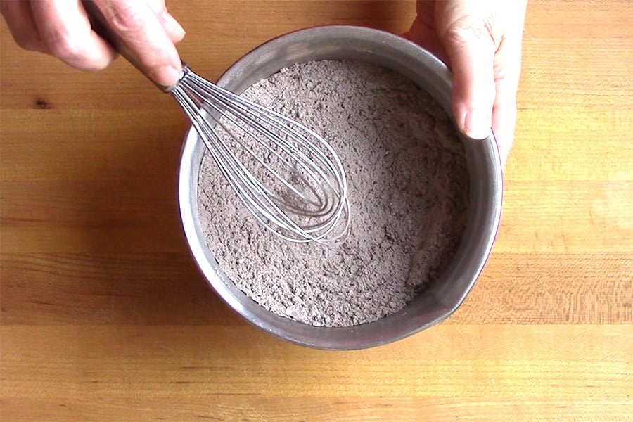 Flour, cocoa powder, baking soda, and salt whisked together in a metal bowl.