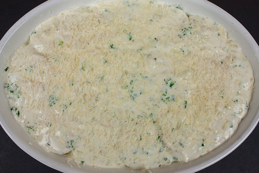 Creamy Herb Potatoes Gratin layered in an oval white casserole dish
