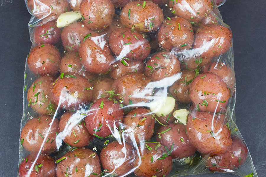 Parboiled baby red potatoes in a zip top bag covered in marinade.