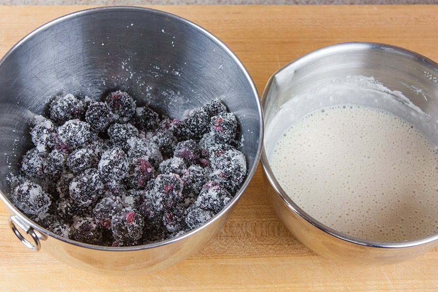 Easy Blackberry Cobbler - blackberries tossed with sugar in a silver mixing bowl next to the batter mix in a silver bowl