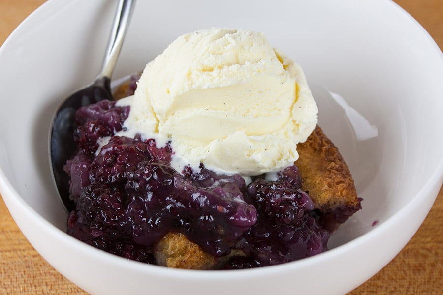 Easy Blackberry Cobbler serving in a white bowl topped with a scoop of vanilla ice cream