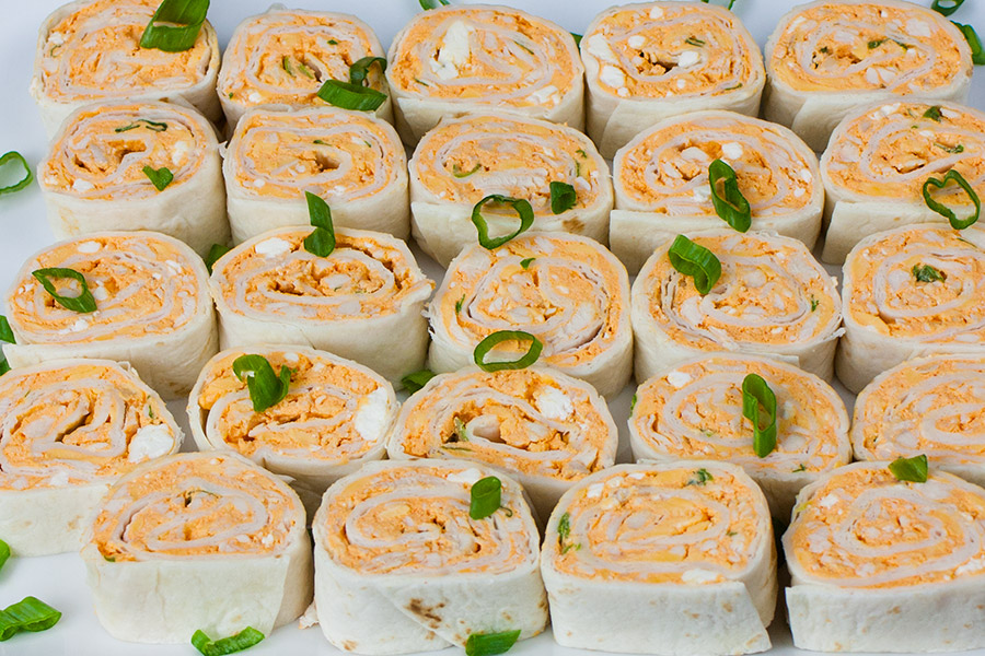 Buffalo Chicken Pinwheel placed next to each other on a platter garnished with diced green onions.